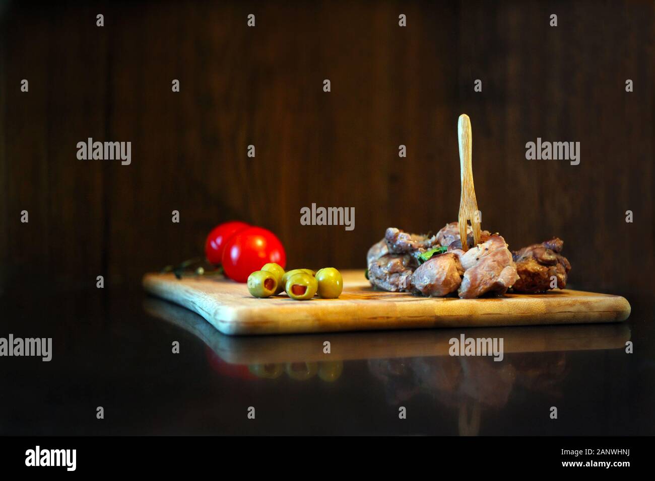 Carne di anatra con pomodori e olive su una tavola di legno. Materie rustico che serve cibo al ristorante. Gourmet di piatti gustosi e concetto di cucina a vista Foto Stock