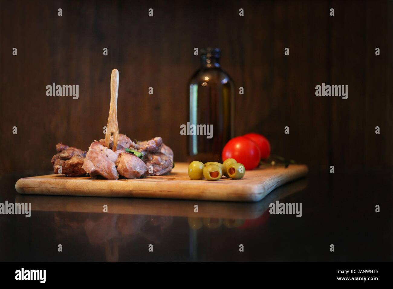 Carne di anatra con pomodori e olive su una tavola di legno. Materie rustico che serve cibo al ristorante. Gourmet di piatti gustosi e concetto di cucina a vista Foto Stock