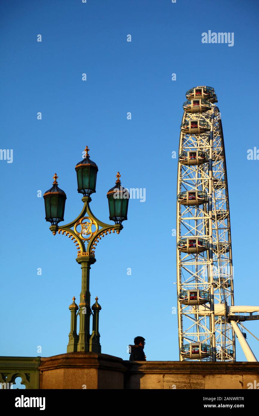 Uomo che cammina passato ornato via lampada sul Westminster Bridge e London Eye / Millennium Wheel, Londra, Inghilterra Foto Stock