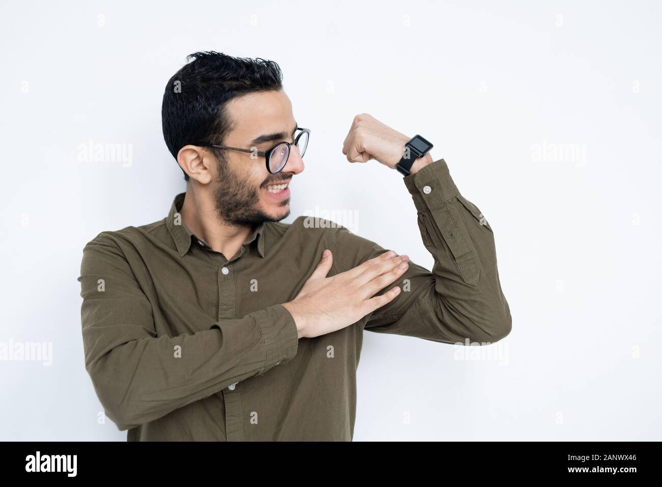 Sorridente giovane uomo forte in occhiali e camicia toccando i suoi muscoli Foto Stock