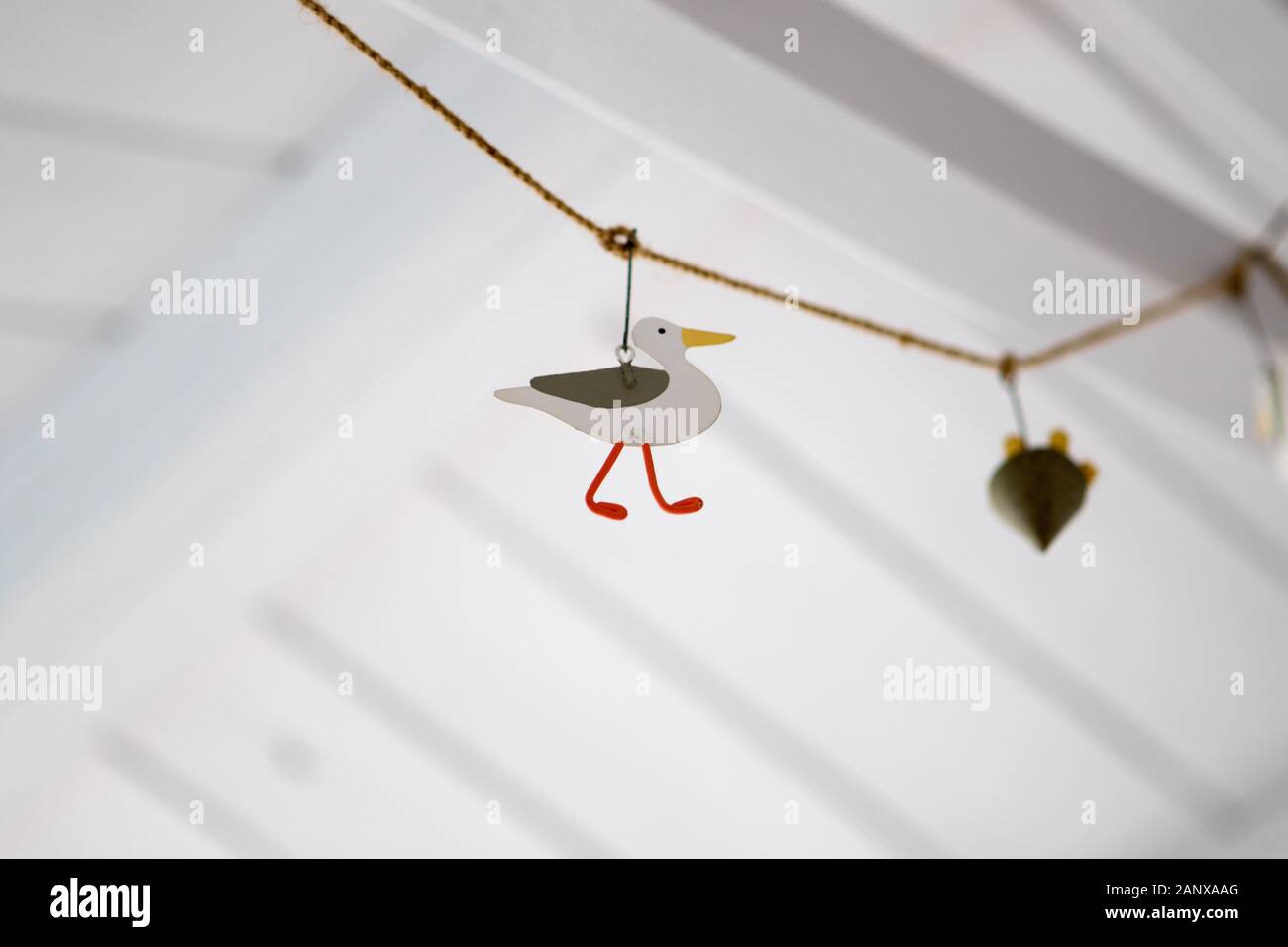 Decorazione di gabbiano appeso su corda dal tetto dipinto di bianco di una capanna di mare a tema nautico Foto Stock