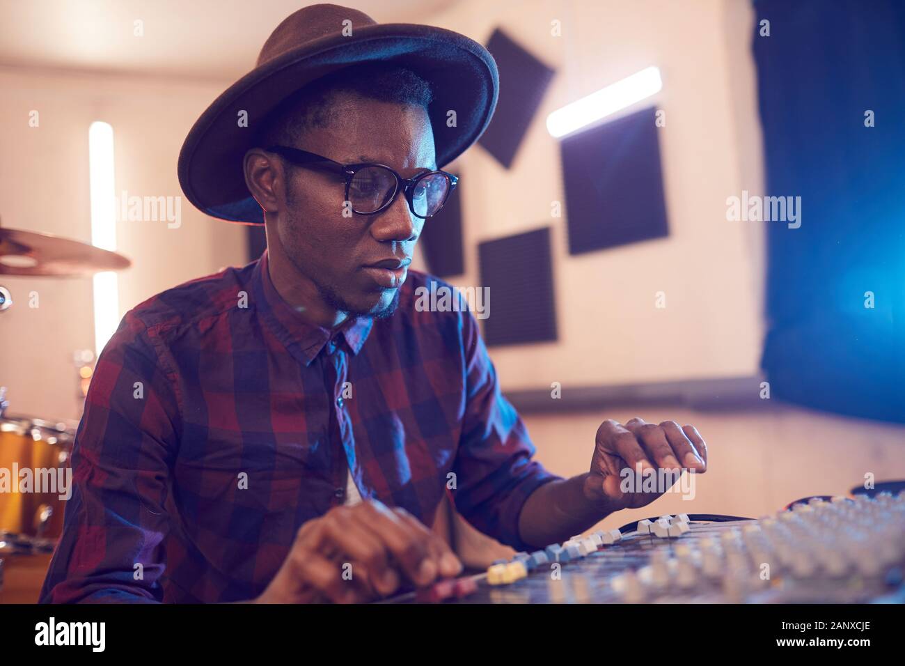 Ritratto di contemporaneo afro-uomo scrivere musica in studio di registrazione audio utilizzando attrezzature di equalizzazione, spazio di copia Foto Stock