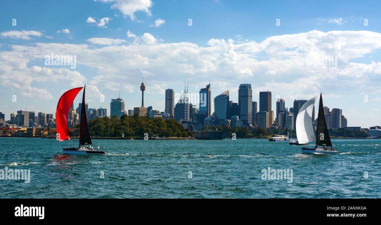 L'iconico skyline di Sydney è incorniciato da due barche a vela colorate che navigano nello splendido porto della città Foto Stock