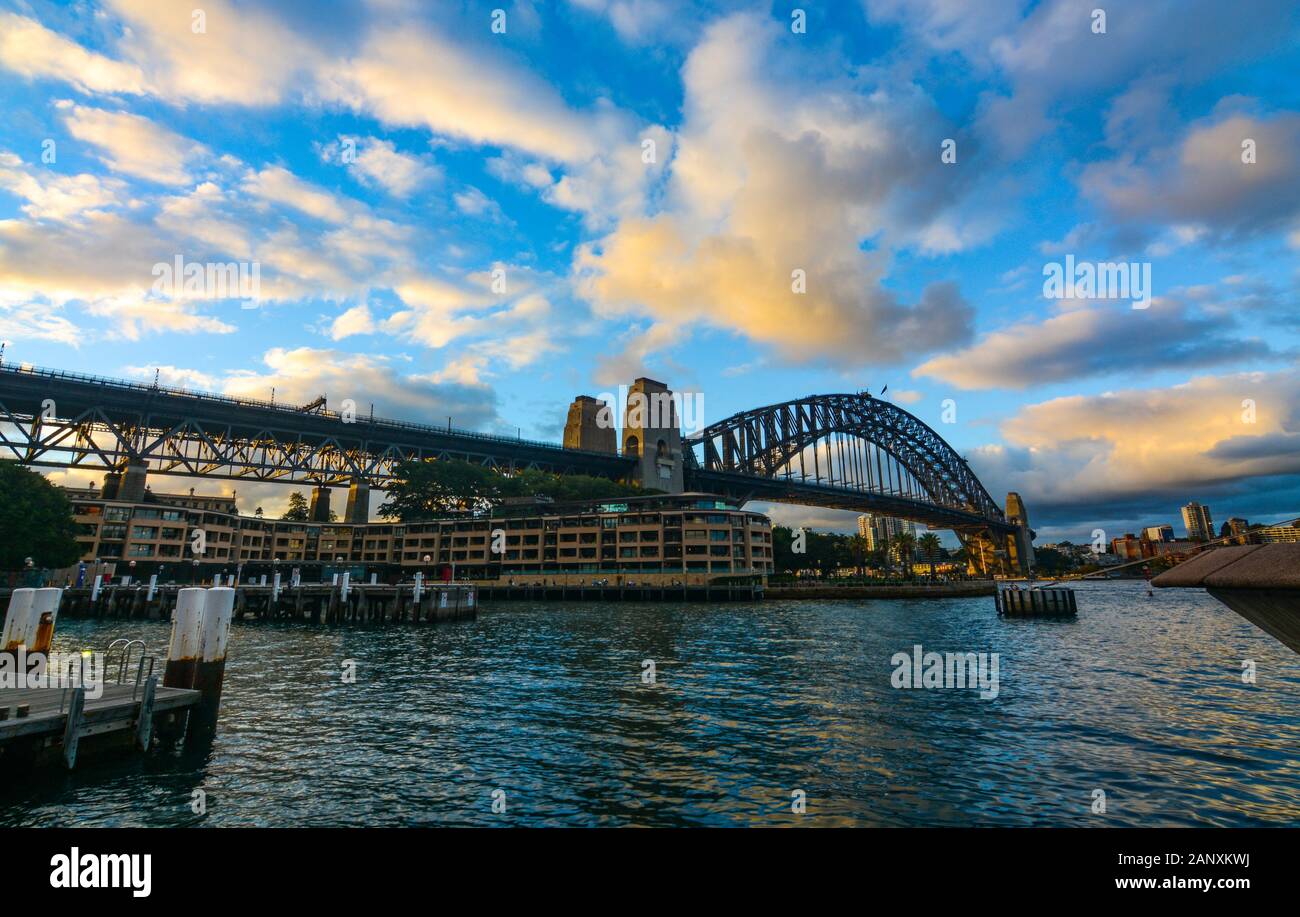 Tramonto e nuvole serali sopra il Sydney Harbour Bridge, come si vede dai moli a Circular Quay Foto Stock