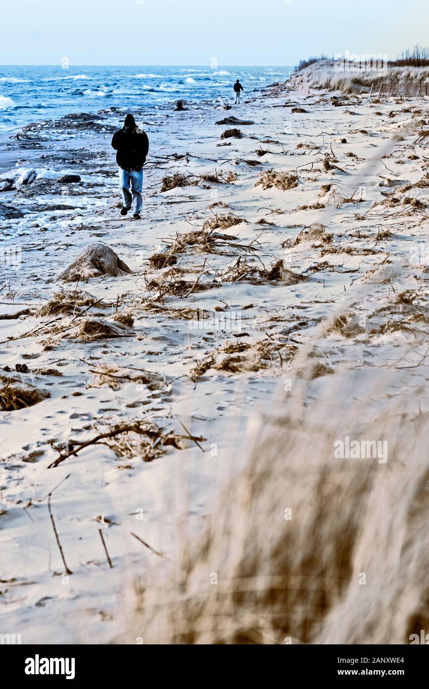 Peson camminando la tempesta disseminato spiaggia vicino al Ludington membro Park Beach House nel dicembre vicino Ludington, Michigan, Stati Uniti d'America Ludington State Park è un Foto Stock