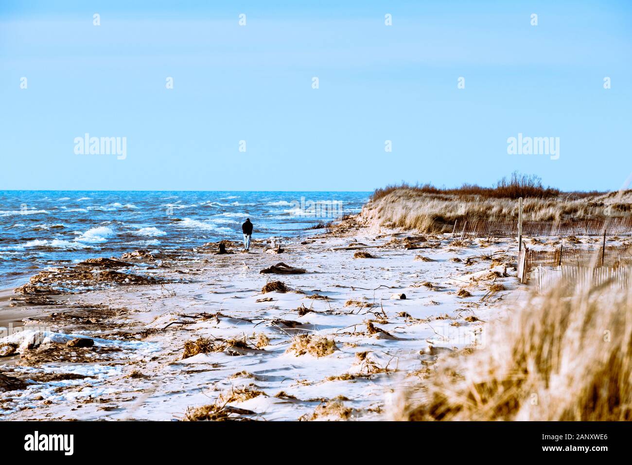 Persona che cammina la tempesta disseminato spiaggia vicino al Ludington membro Park Beach House nel dicembre vicino Ludington, Michigan, Stati Uniti d'America Ludington parco dello stato è Foto Stock