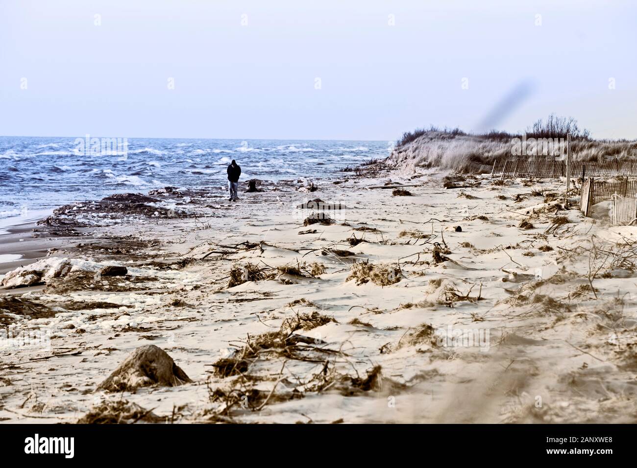 Peson camminando la tempesta disseminato spiaggia vicino al Ludington membro Park Beach House nel dicembre vicino Ludington, Michigan, Stati Uniti d'America. Ludington parco dello stato è Foto Stock