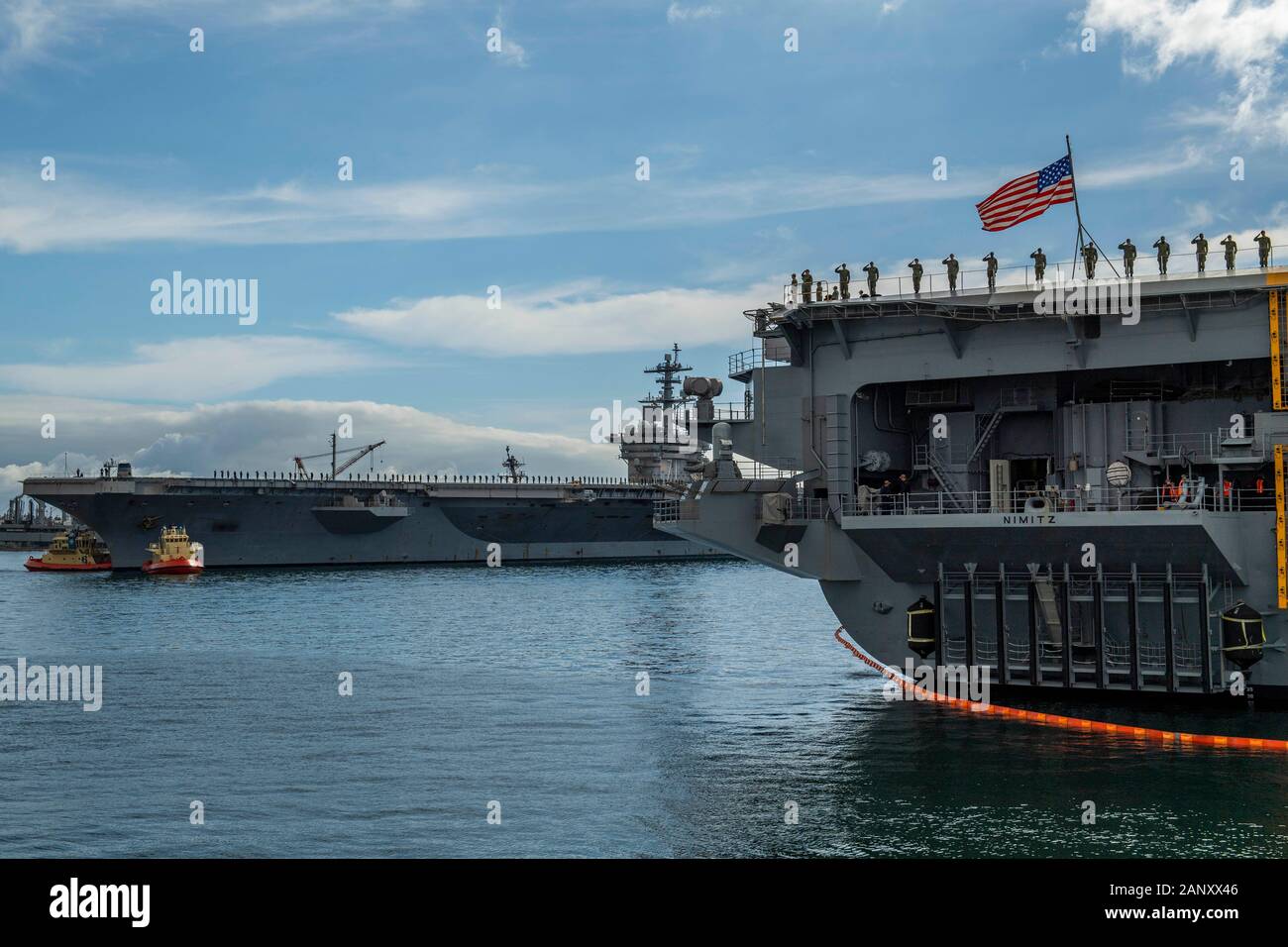 200118-N-SS350-1149 SAN DIEGO (GEN. 17, 2020) i marinai a bordo della Nimitz-class portaerei USS Nimitz CVN (68), a destra, l'uomo le rotaie e rendere onore a la Nimitz-class portaerei USS Theodore Roosevelt CVN (71) è tirato fuori il suo ormeggio nel porto di San Diego per la distribuzione. Theodore Roosevelt Carrier Strike gruppo è su un regolari Indo-pacifico distribuzione per promuovere costanti la pace, la sicurezza e la stabilità in tutto il Pacifico teatro delle operazioni. Foto Stock