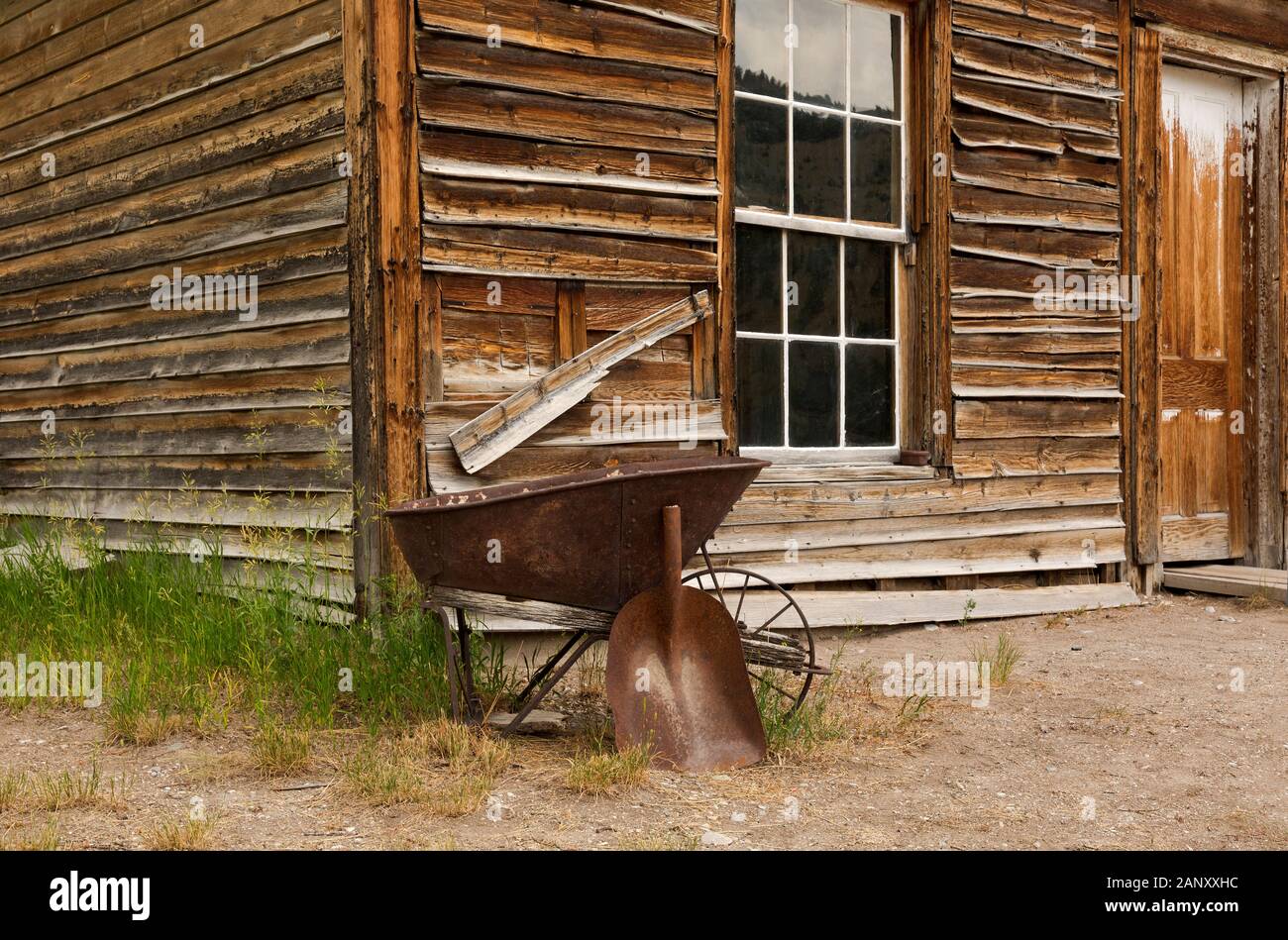 MT00395-00...MONTANA - Vecchia carriola e la pala al di fuori di uno degli edifici più antichi conservati presso la città fantasma di Bannack in stato di Bannack Park. Foto Stock