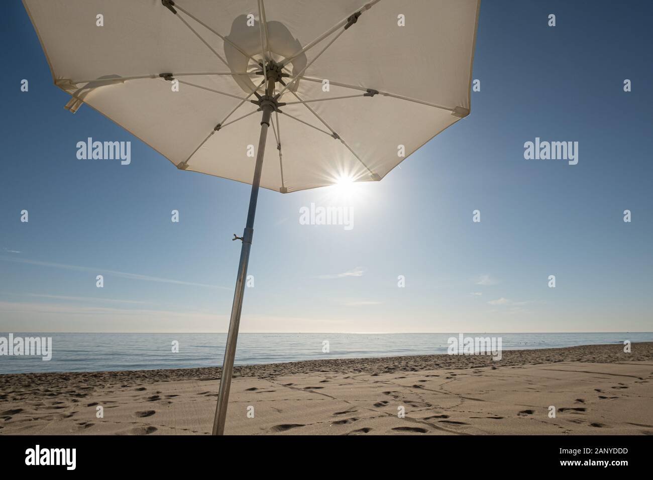 Ombrellone bianco al sole e cielo blu sulla spiaggia di carihuela a Torremolinos Spagna Foto Stock