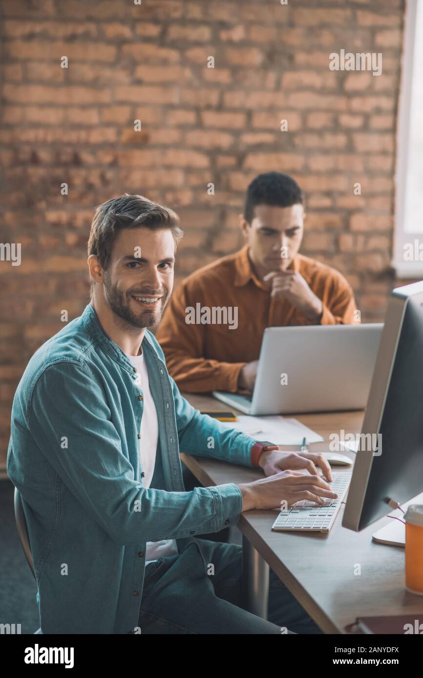 Allegro smart uomo seduto davanti al suo computer Foto Stock