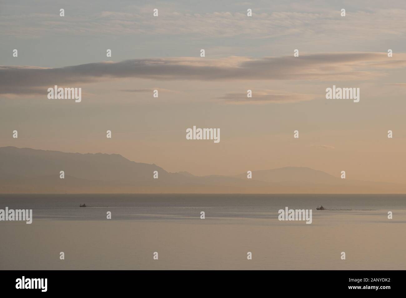 vista panoramica del mare calmo e barca da pesca in nebbia la mattina presto luce Foto Stock