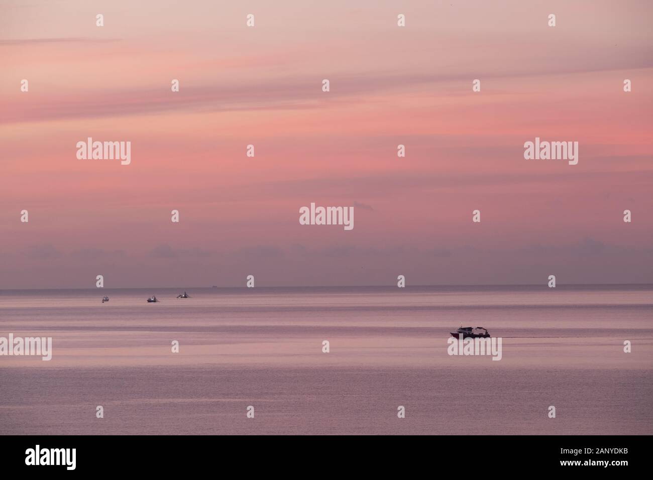 vista panoramica del mare calmo e barca da pesca in nebbia la mattina presto luce Foto Stock