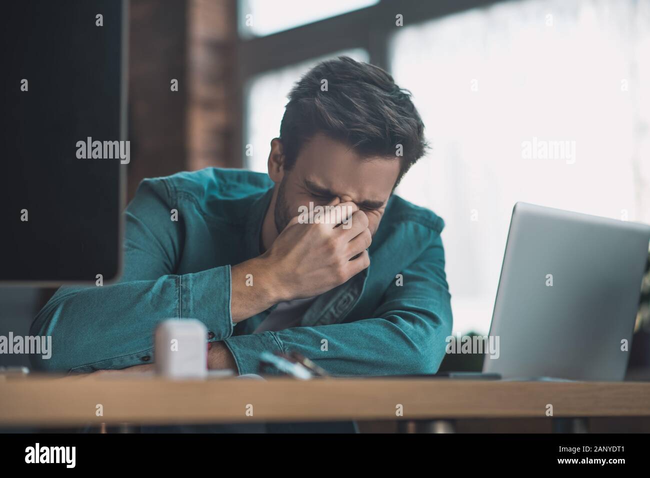 Infelice cupa uomo toccando il ponte del naso Foto Stock