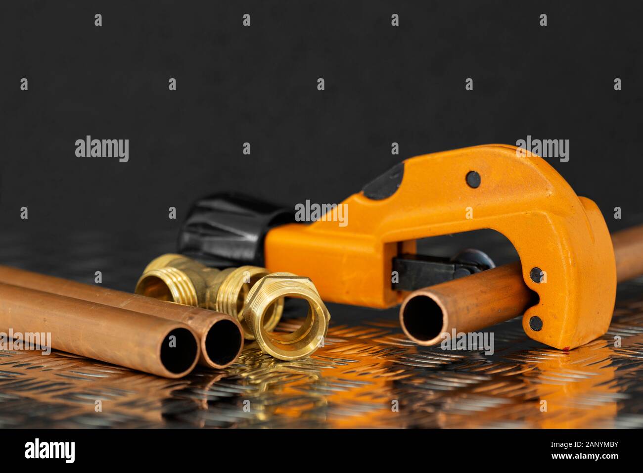 Tubo di rame e fresa con connettori idraulici su un acciaio checker superficie di lastra. Strumento di tubazioni e pezzi di ricambio Foto Stock
