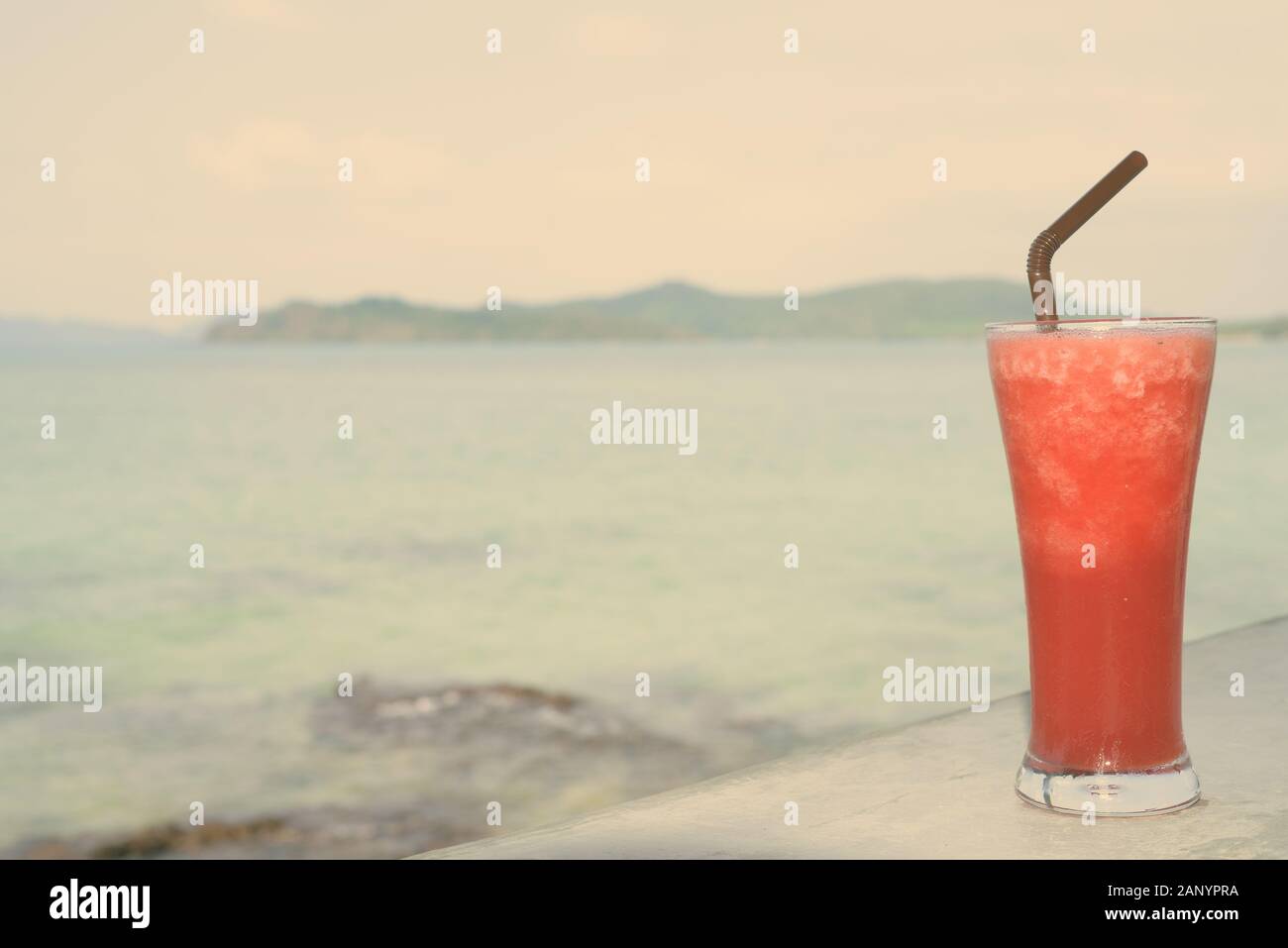 Rinfrescante frullato di anguria contro la vista della spiaggia Foto Stock