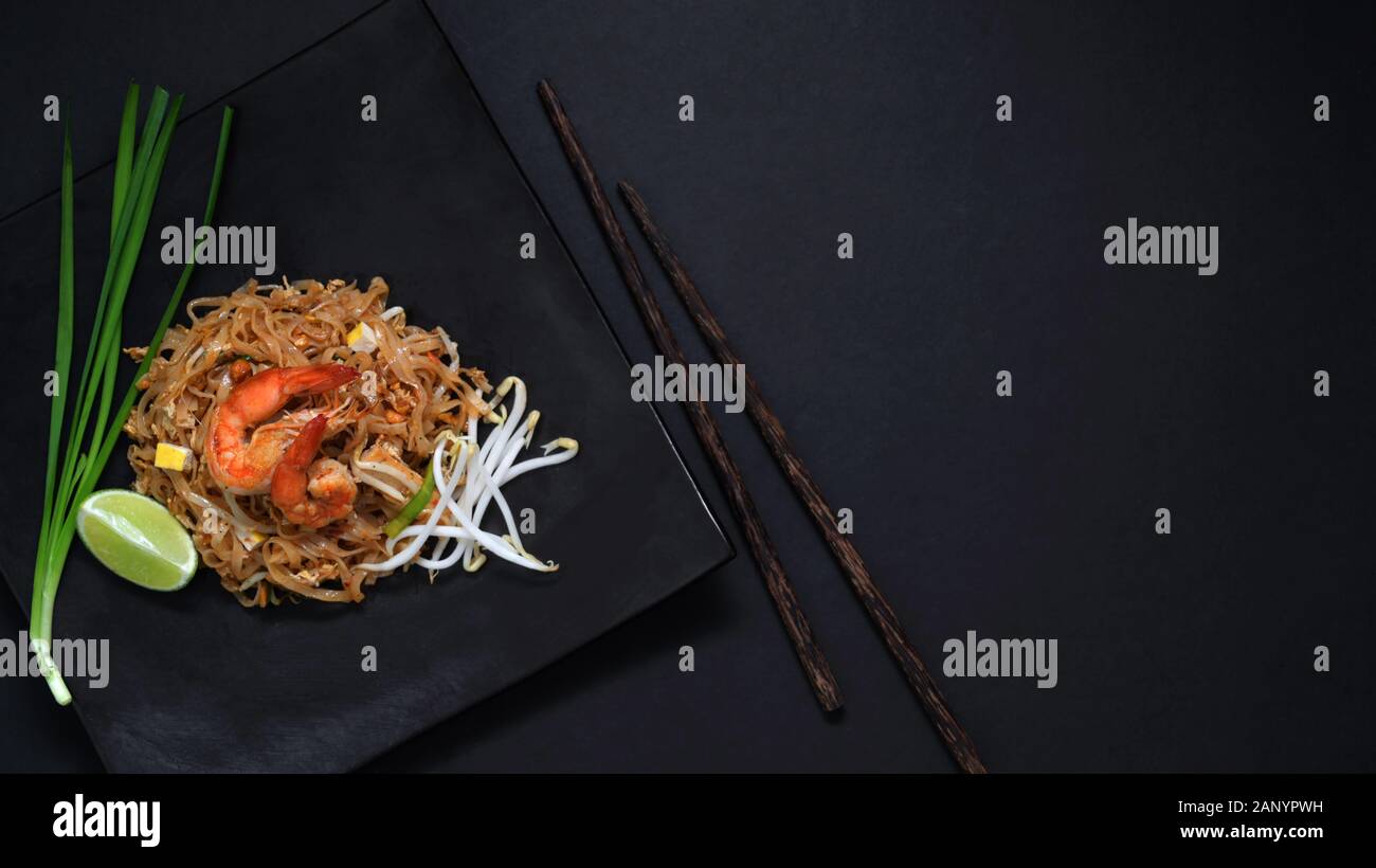Vista superiore del Pad Thai, agitare fly di Thai noodle con gamberi e uova in nero piastra in ceramica con copia spazio sulla tavola nera Foto Stock