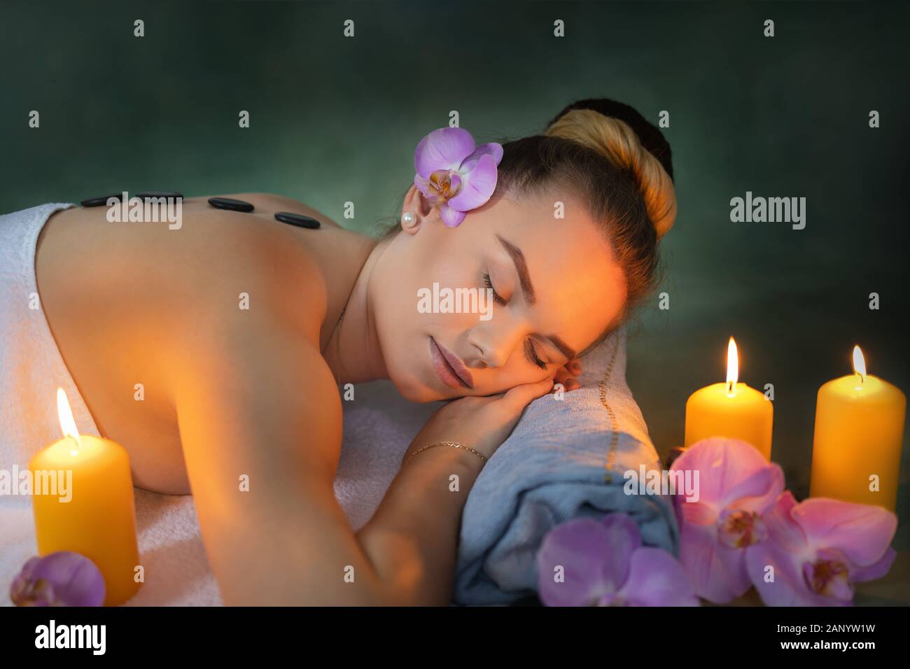 Giovane donna che si rilassa durante un massaggio in pietra calda in una lussuosa spa Foto Stock