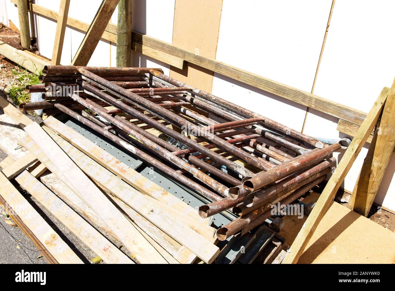 Pila di tubi di metallo e tronchi di legno vicino a. un edificio catturato all'ora del giorno Foto Stock