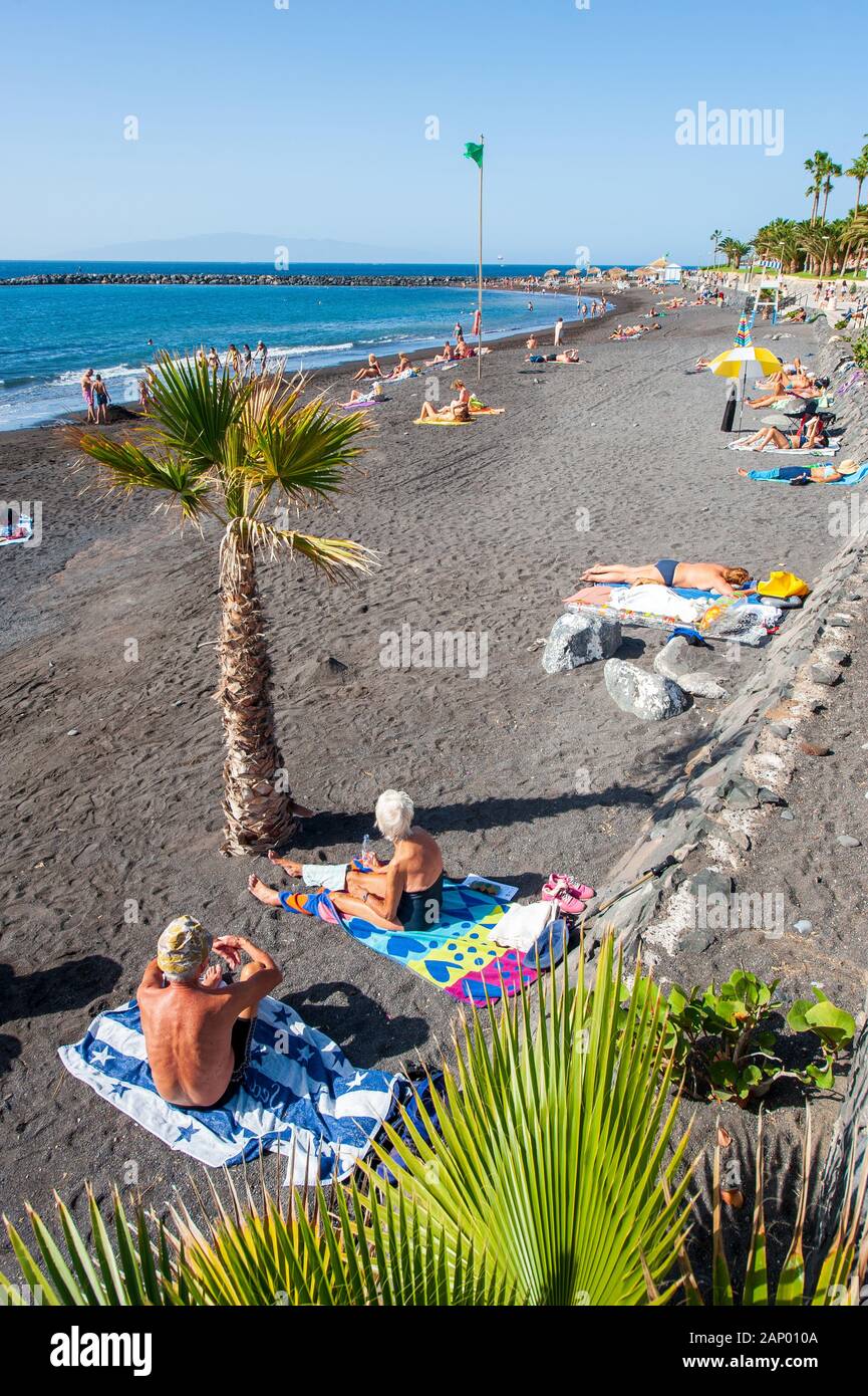 Isola Canarie TENERIFE, Spagna - 27 Dic, 2019: i turisti sono rilassanti e giocare su una spiaggia chiamata Playa El Beril su Tenerife. Una spiaggia di ghiaia nera. Foto Stock