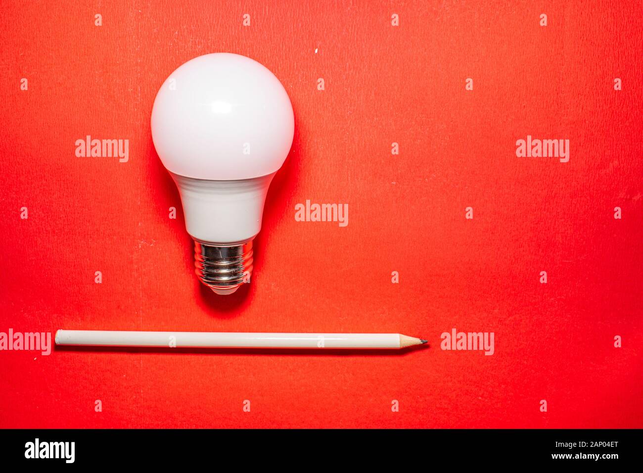 La luce bianca lampadina e una penna bianca su sfondo rosso. idea che appaiono e rilevato. Foto Stock