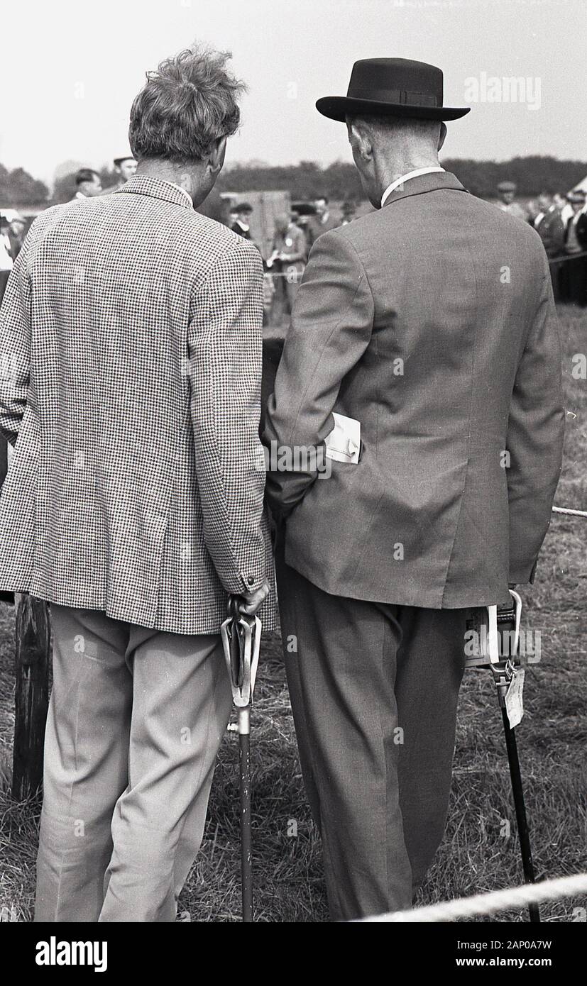 Anni sessanta, storico, due colleghi, uno con il cappello e con i loro bastoni di ripresa in visita a una fiera di paese, Thame Visualizza, Buckinghamshire, Inghilterra, Regno Unito. Foto Stock