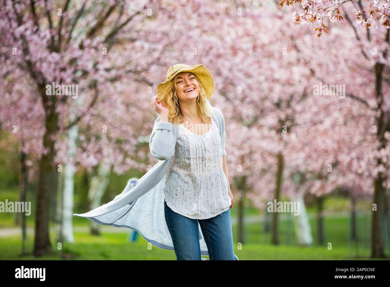 Giovane donna che gode la natura in primavera. Danza, corsa e vorticoso in un bellissimo parco con ciliegi in fiore. Concetto di felicità Foto Stock