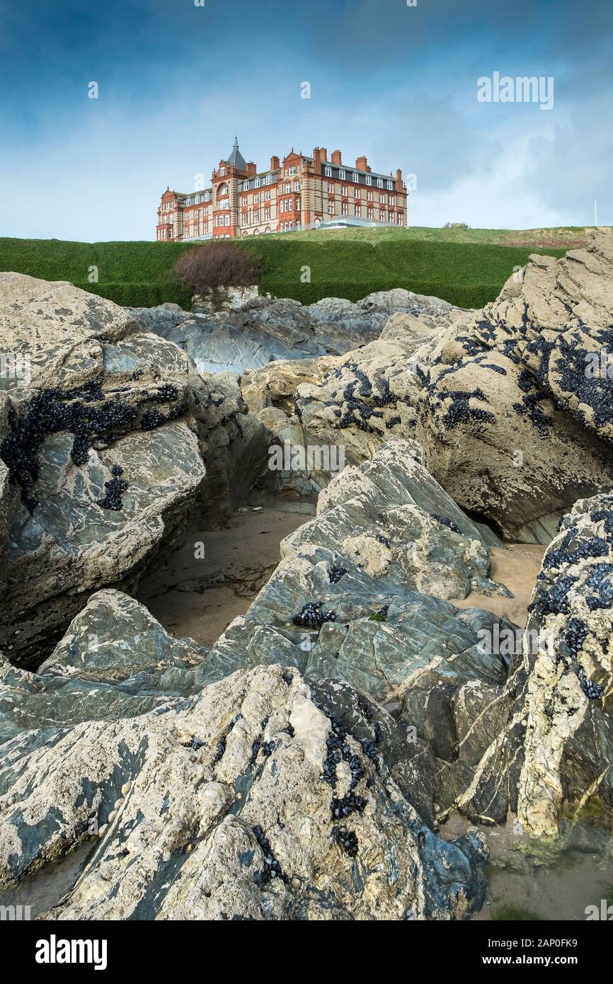 Headland Hotel che si affaccia su rocce esposte a bassa marea sulla costa a Fistral a Newquay in Cornovaglia. Foto Stock