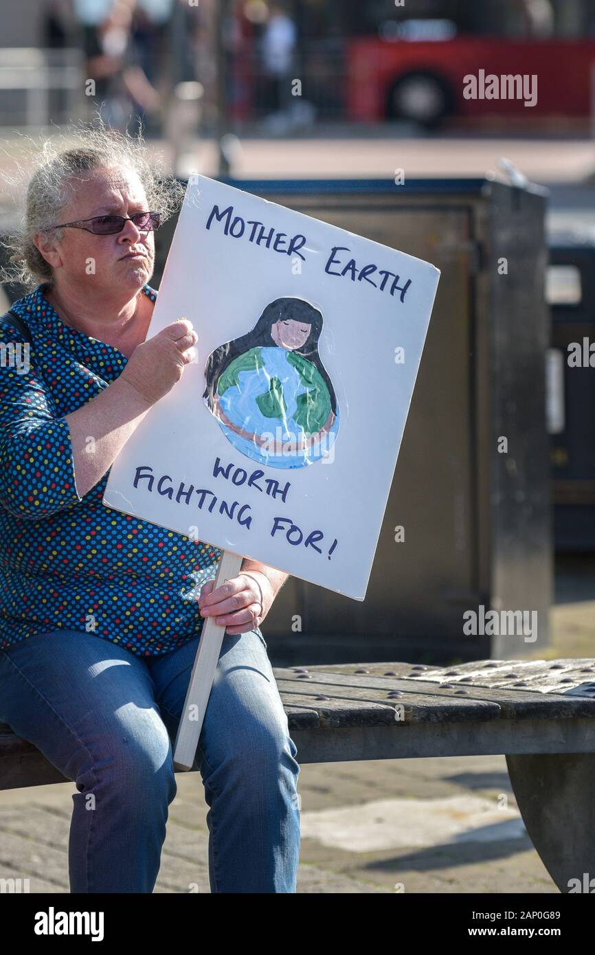 Una donna matura tenendo un cartello e che partecipano alla estinzione della ribellione clima sciopero in Truro City in Cornovaglia. Foto Stock