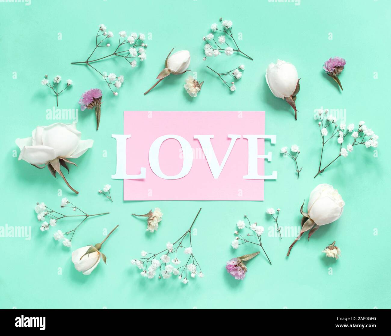 La crema di rose e amore di testo su uno sfondo verde chiaro vista superiore Foto Stock