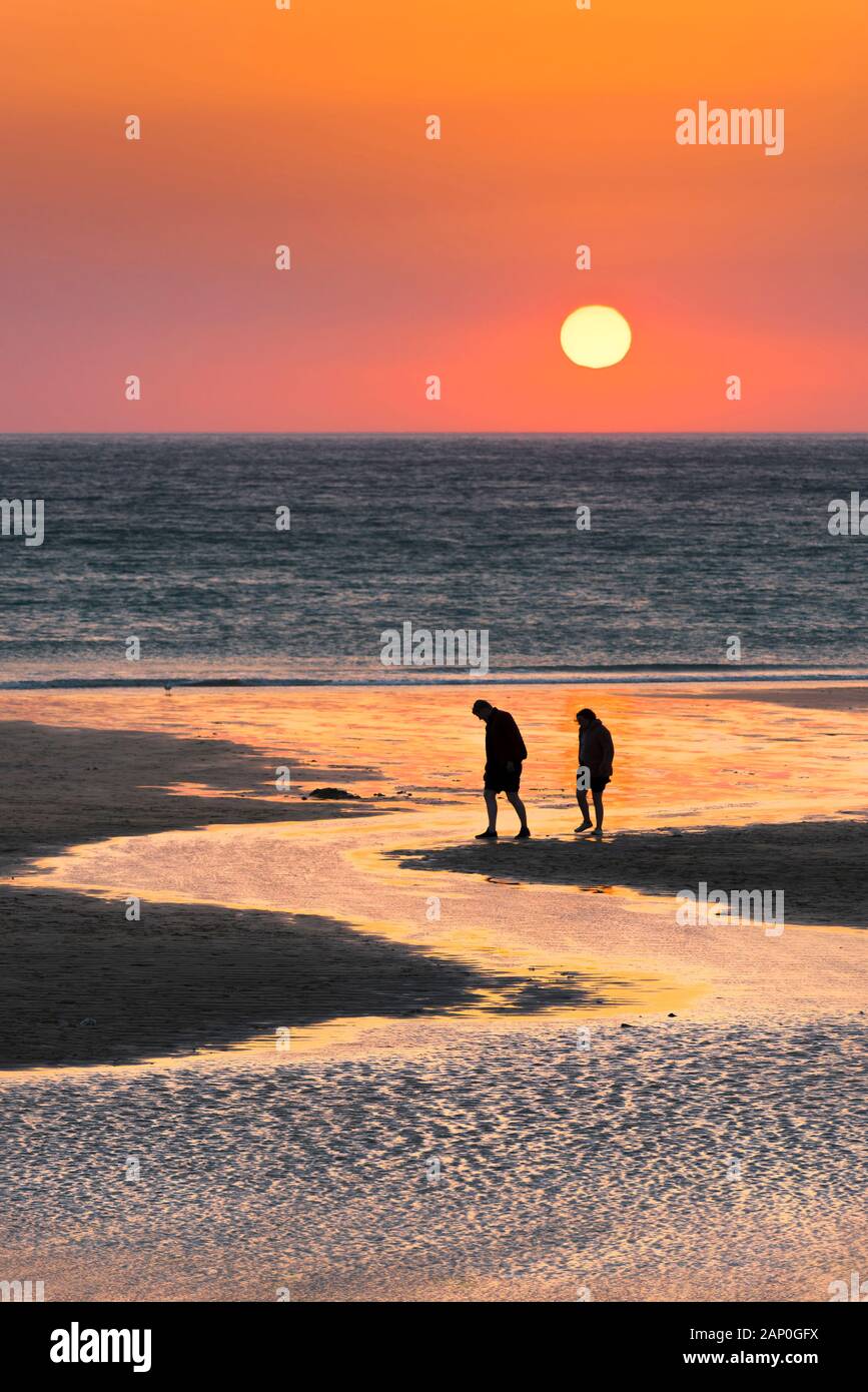 La gente vede in silhouette contro un bel tramonto a Fistral Beach in Newquay in Cornovaglia. Foto Stock
