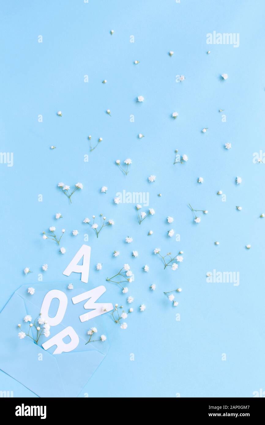 Busta blu, testo AMOR e piccoli fiori bianchi su sfondo azzurro vista superiore Foto Stock