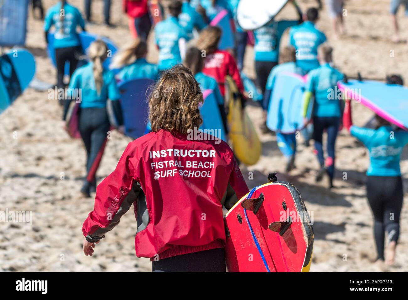 Un istruttore di surf con il Fistral Beach Surf School l'impostazione off per tenere una lezione di surf a Newquay in Cornovaglia. Foto Stock
