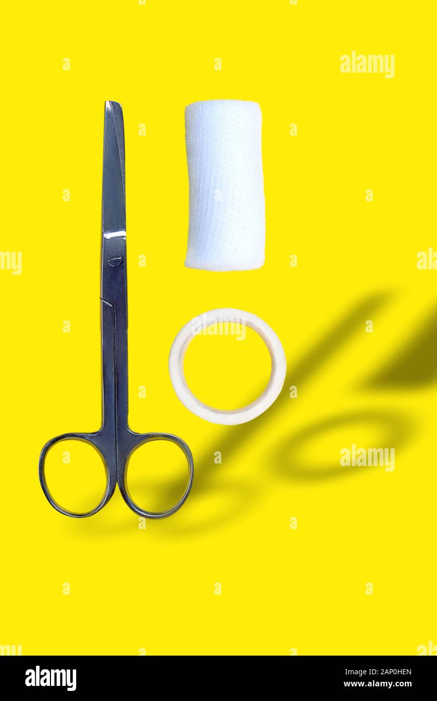 Forbici, bende e Band-aiuto con ombra su sfondo giallo, il concetto di medicina Foto Stock