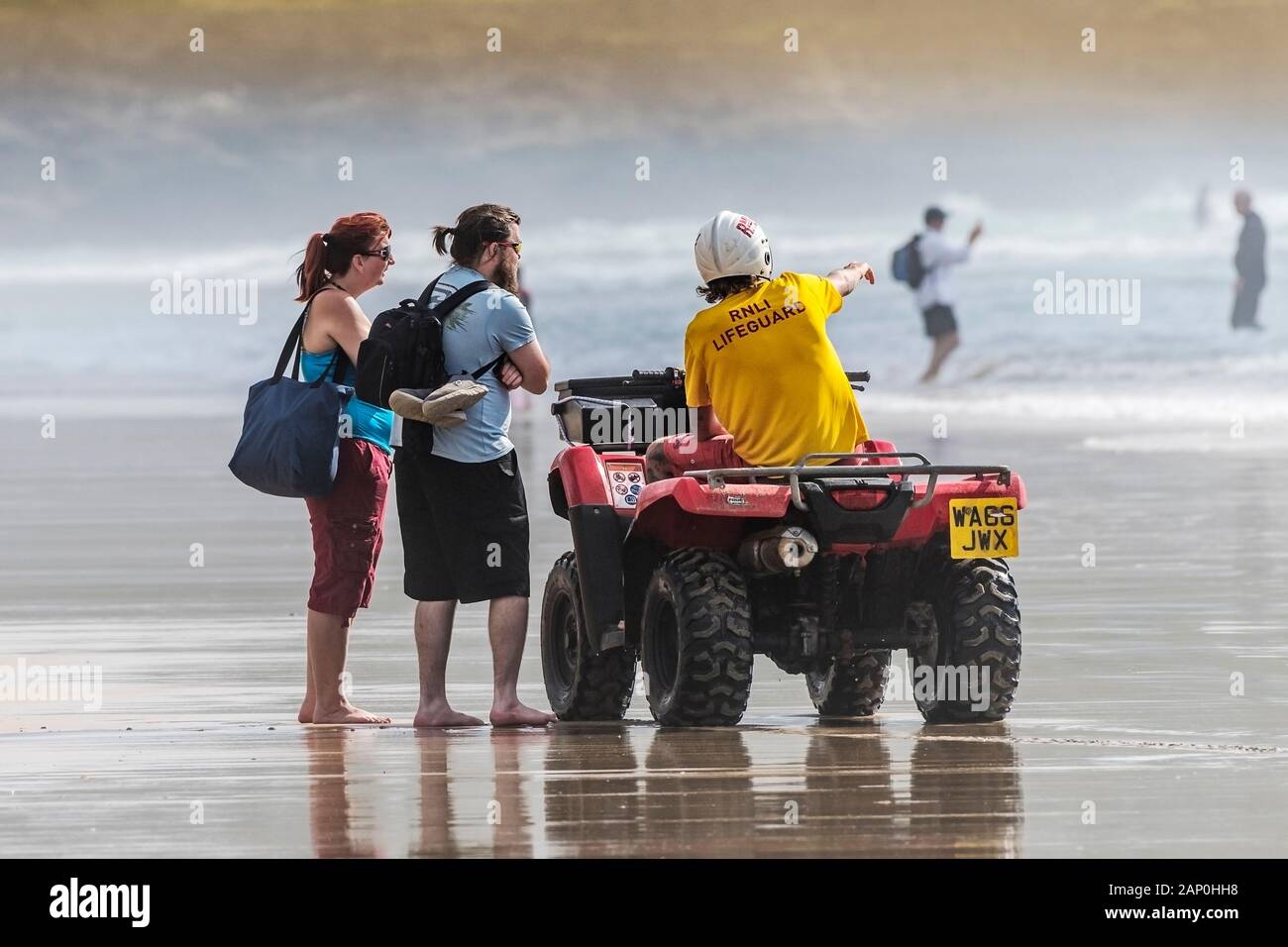 Un bagnino RNLI consigliare i turisti alla sicurezza di aree di balneazione Fistral Beach in Newquay in Cornovaglia. Foto Stock