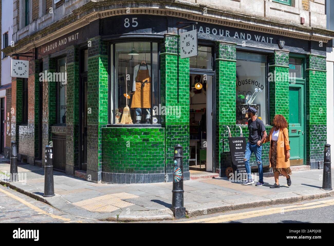 Una giovane coppia a piedi passato del lavoro e attendere vintage casa store su Redchurch Street in Shoreditch. Foto Stock