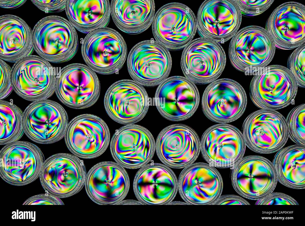 Schemi di sollecitazione colorati in contenitori in plastica rigida con tappo a vite rivelati dall'imaging tra due filtri polarizzanti incrociati. Foto Stock