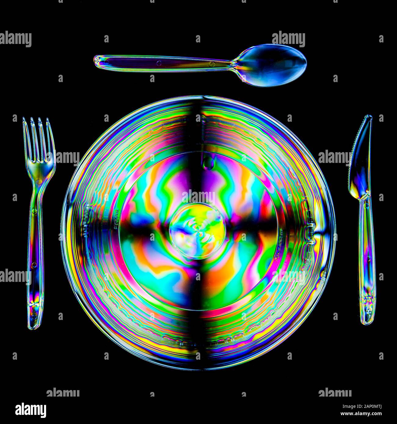 Colorate sequenze di stress in plastica dura, rivelate dall'imaging tra due filtri polarizzanti incrociati e mostrando una piastra, un coltello, una forchetta e un cucchiaio. Foto Stock
