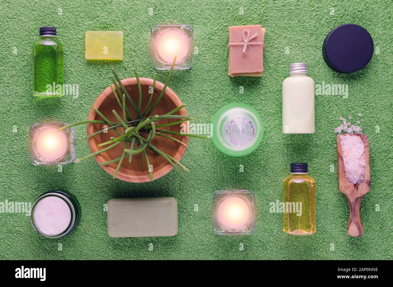 Wellness e Spa prodotti, shampoo, crema, lozione, sapone, sale rosa e piante con candele su verde Foto Stock