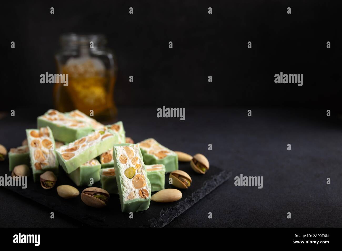 Torrone di organico a base di miele, pistacchi, nocciole, mandorle e i dadi su un rustico sfondo scuro. Foto Stock