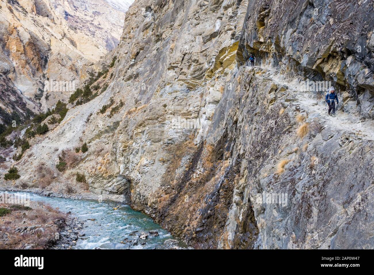 Trekking su un sentiero stretto attraverso una gola sul Sentiero Inferiore del Dampo in Nepal Foto Stock