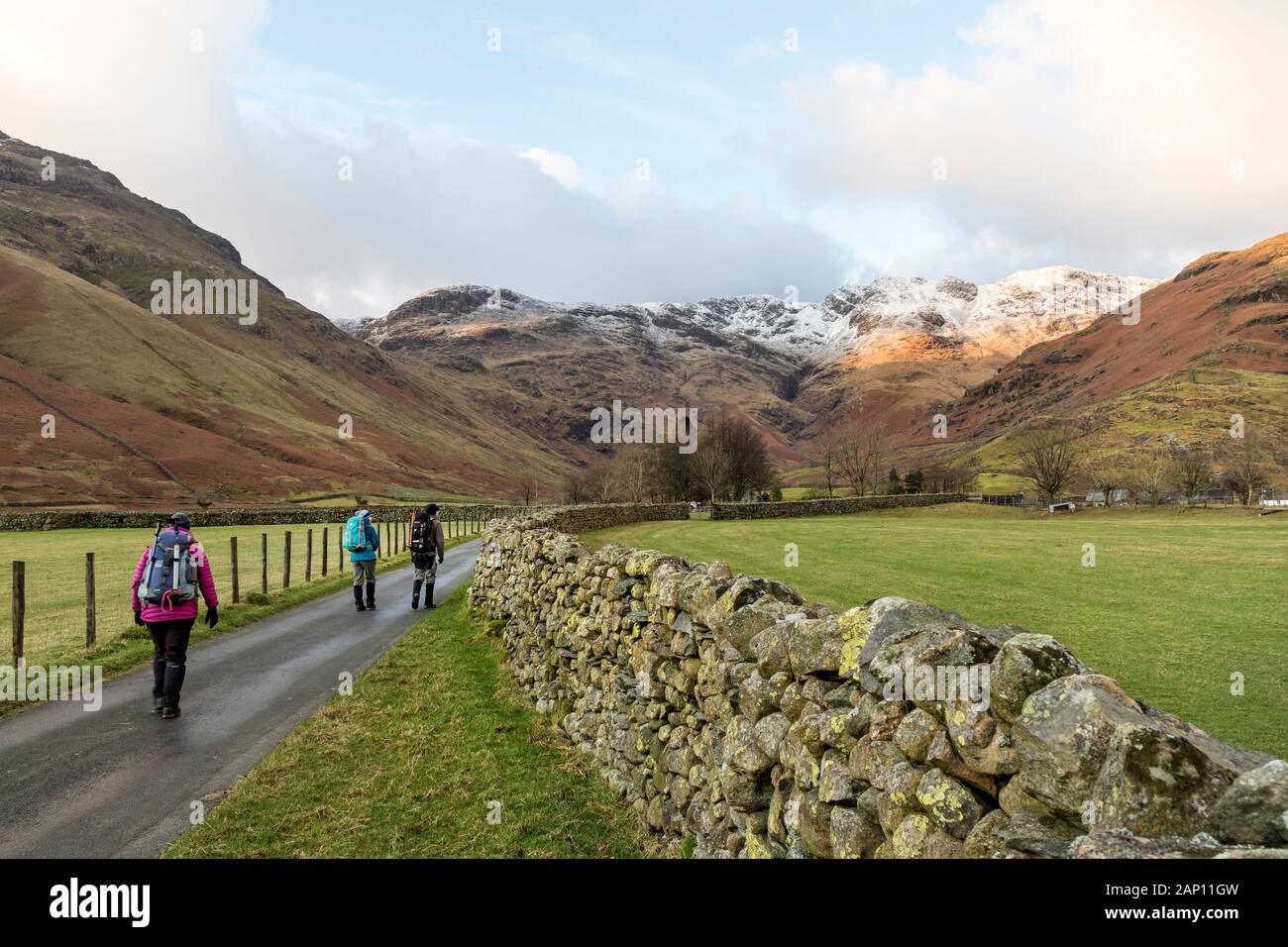 Walkers dirigendosi verso uno sgabello fine fattoria con Crinkle Crags avanti, Lake District, Cumbria, Regno Unito Foto Stock