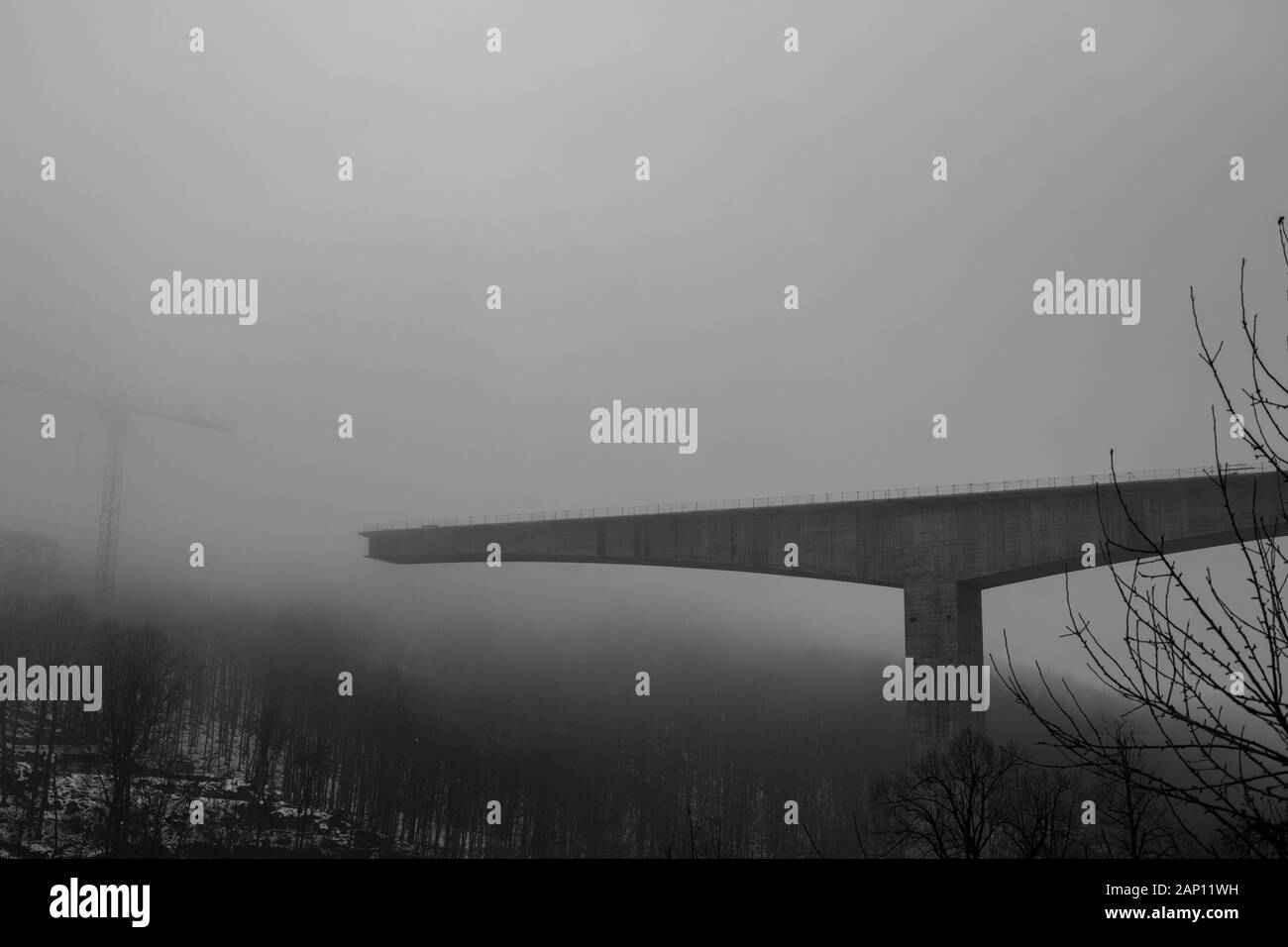 Fitta nebbia invernale e costruzione di ponti in cemento ad alta velocità nella città di Gabrovo, nel nord della Bulgaria, in Europa. Parte della circonvallazione, sponsorizzata dall'Unione europea. Immagine in bianco e nero Foto Stock