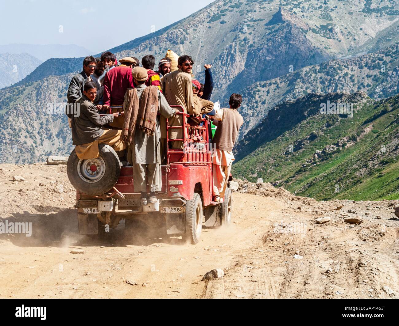 Le persone sono aggrappate a una jeep sovraccarica, guidando sulla strada polverosa fino al passo Babusar Foto Stock