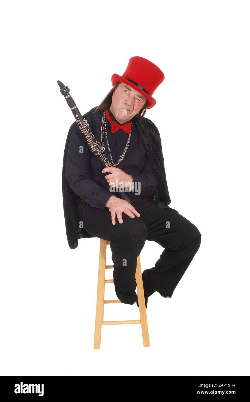 Un Medioevo uomo indigeni tenendo la sua clarinetto in un abito nero e Red Hat ed il filtro bow tie guardando lontano, isolato per sfondo bianco Foto Stock