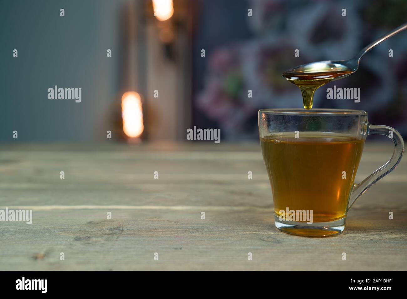 Tè caldo a casa con un cucchiaio di miele che gocciola nel tè Foto Stock
