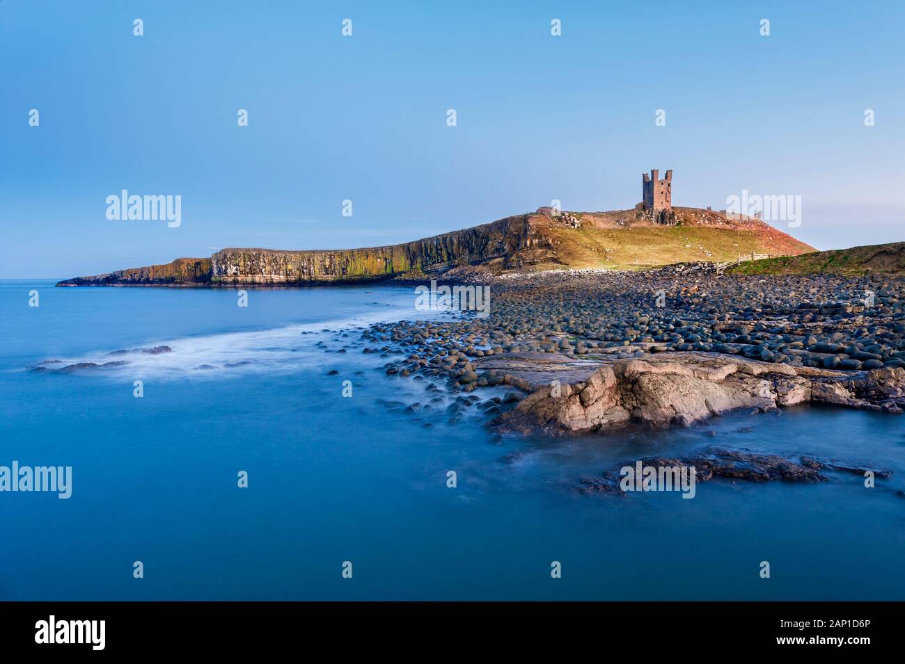Dunstanburgh Castle e rocciosa e coperta di boulder litorale di Embleton Bay sulla costa di Northumberland Foto Stock