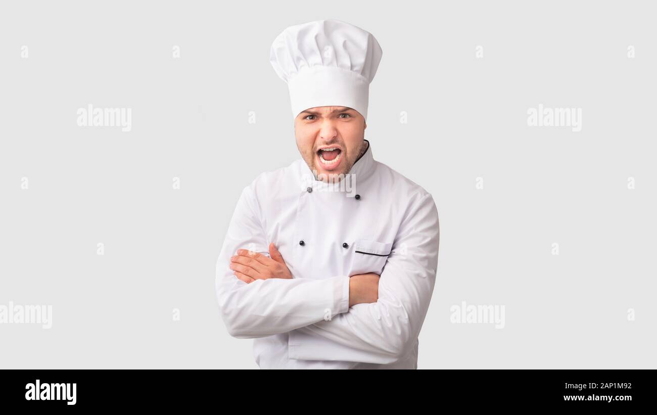 Arrabbiato Chef uomo grida attraversando le mani in piedi in studio, Panorama Foto Stock