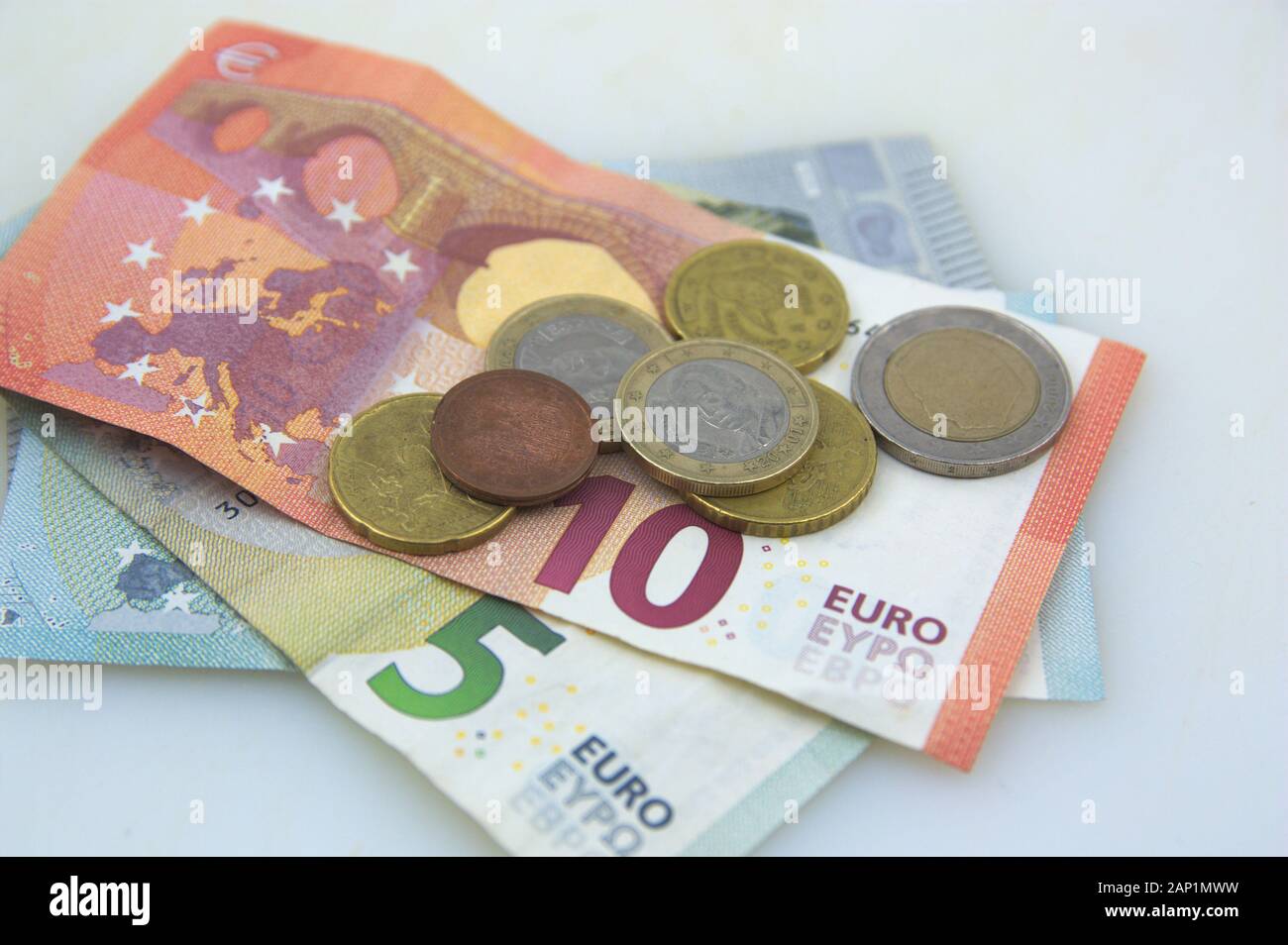 Close-up di 10 e 5 euro le fatture in cui vi sono alcuni cent di euro monete tutte su un tavolo bianco Foto Stock