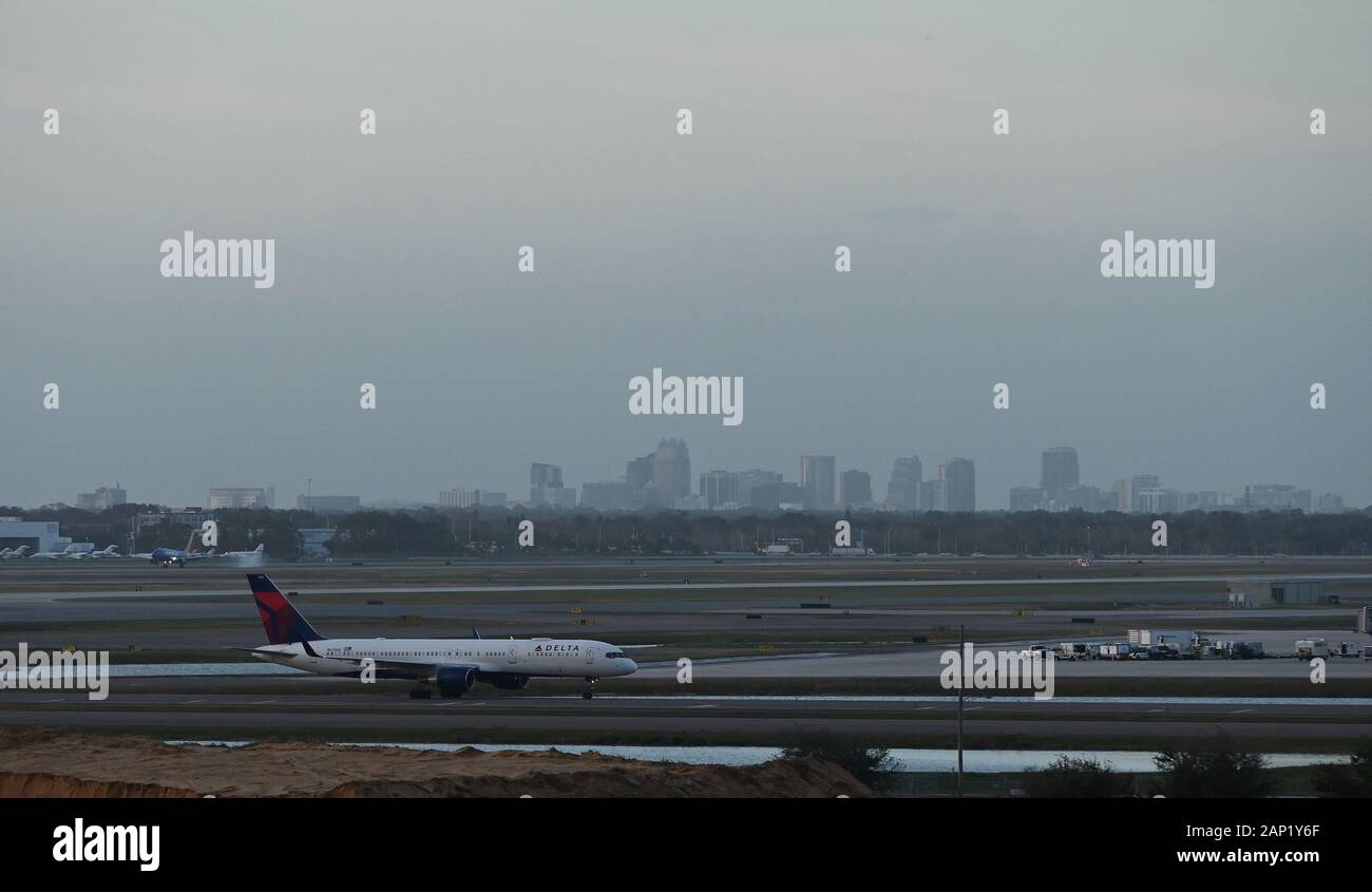 Un aereo Delta Airlines che tassava con il centro di Orlando, Florida, sullo sfondo dell'aeroporto internazionale di Orlando. Foto Stock